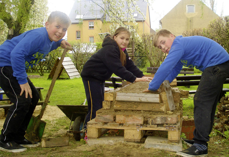 Drei Kinder bauen mit Lehm