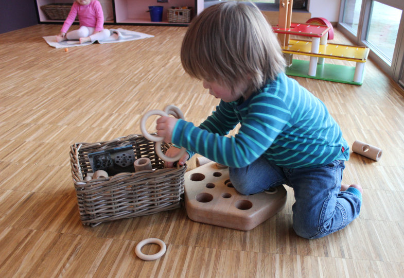 Kind räumt das Spielmaterial in Körbe