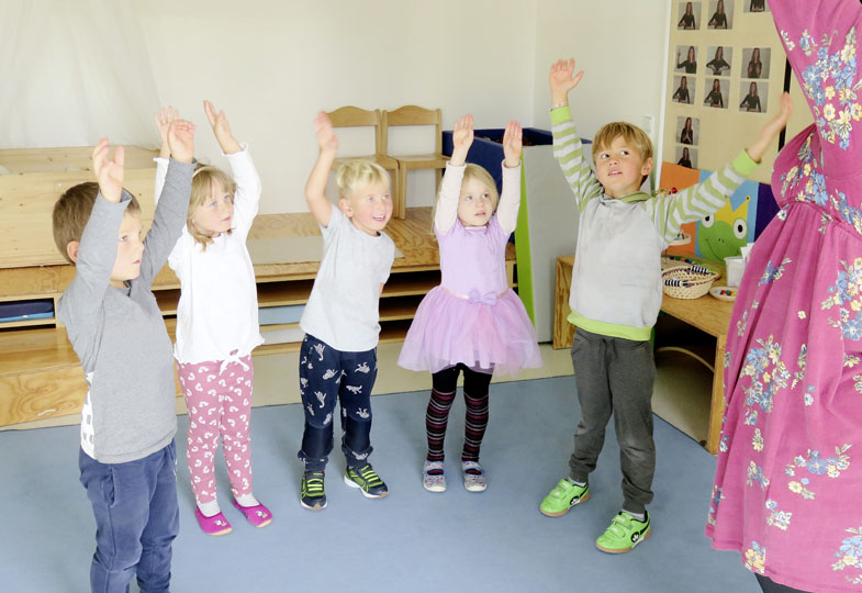 Kinder stehen im Kreis und heben die Hände