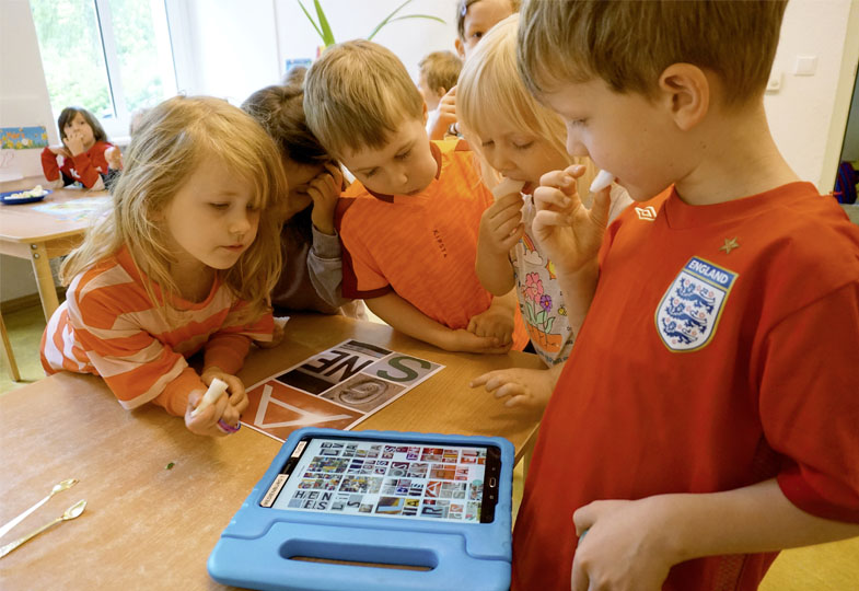 Kinder schauen sich eine Fotocollage auf dem Tablett an