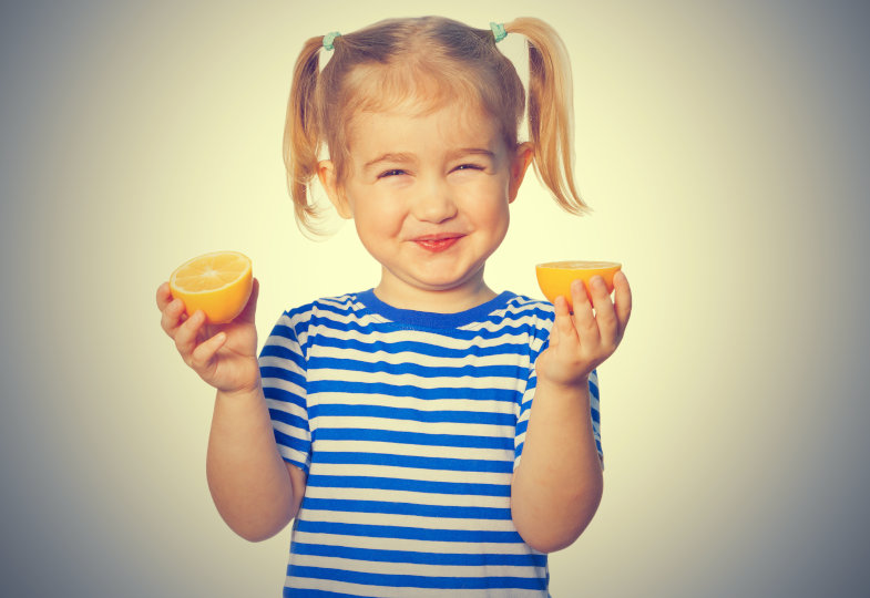 Kind hält zwei Orangenhälften in der Hand