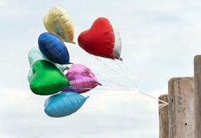 Luftballons in Herzform flattern an einem Holzpfahl