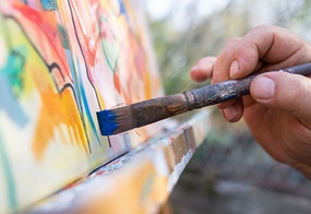 Eine bunt bemalte Leinwand mit einem Pinsel mit blauer Farbe. 