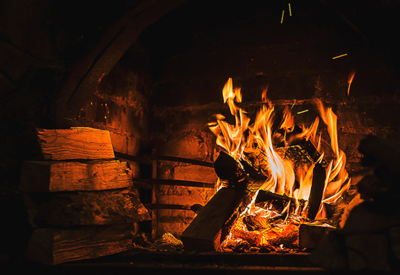 Der Hintergrund ist dunkel und in der Mitte brennt ein Feuer mit orangenen und roten Flammen.