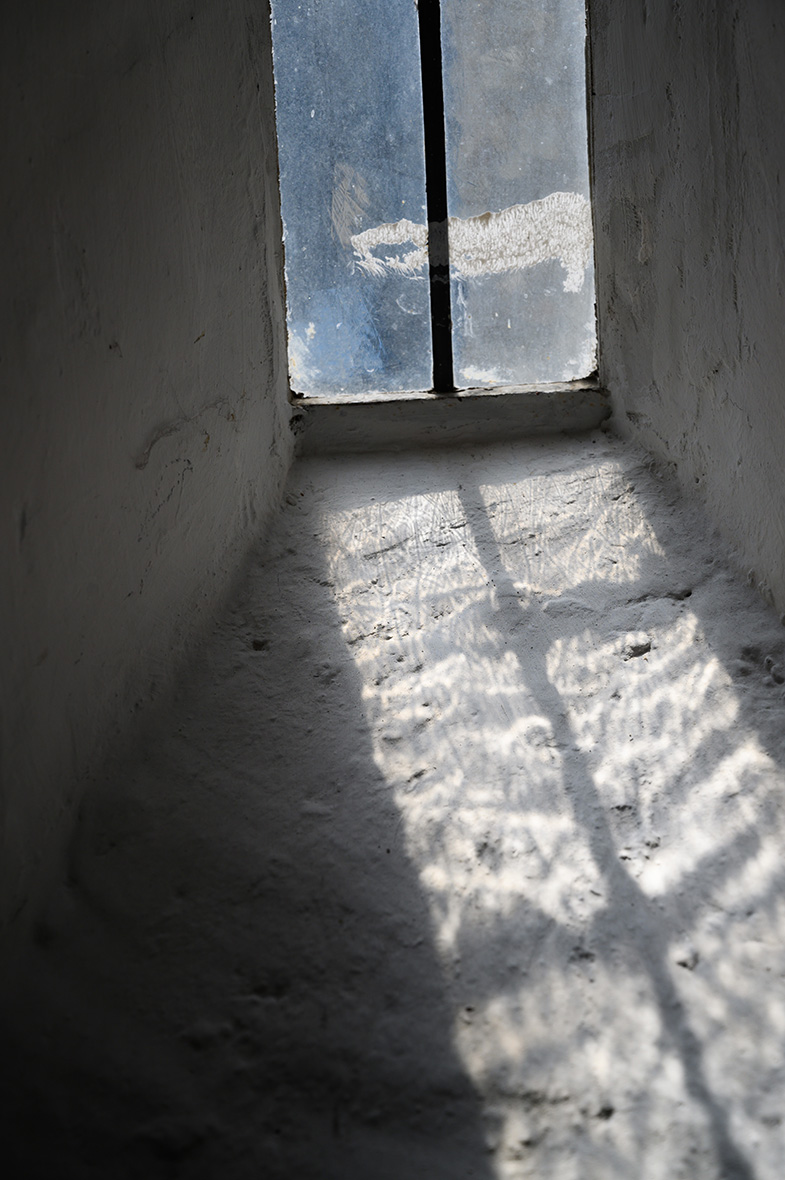Aus der Untersicht blickt man in einen schachtartigen Aufgang, an dessen oberem Ende ein trübes Fenster Licht hereinlässt.