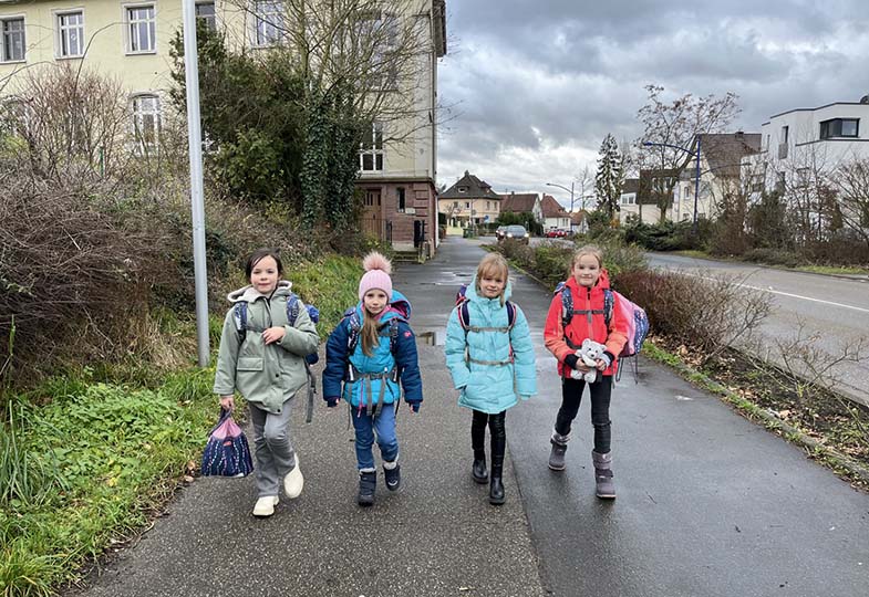 Vier Kinder gehen zusammen auf einem Gehweg.
