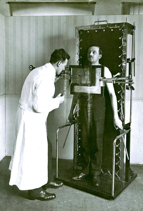 Ein Arzt checkt Daten auf einer Apparatur, in der ein Patient steht.