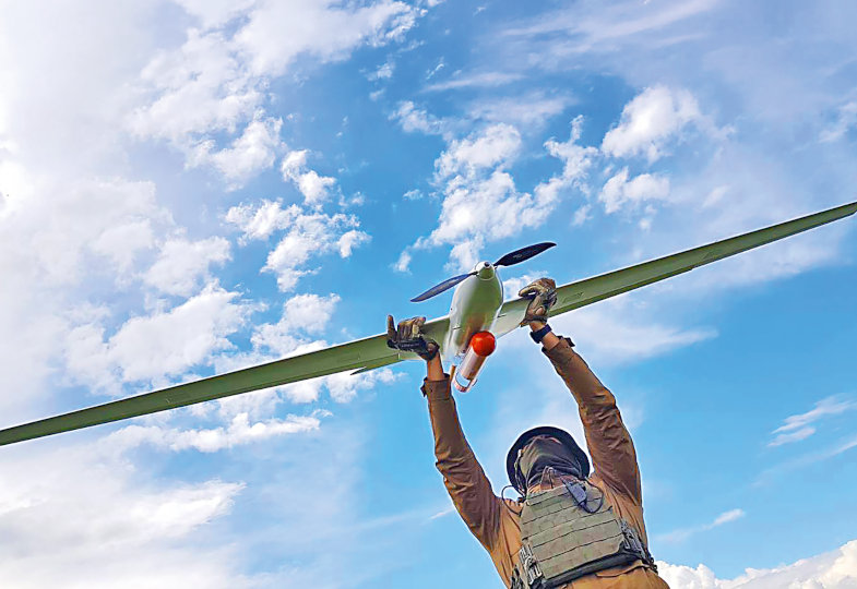 Blick von unten: Ein Mann hält eine Drohne in den Himmel