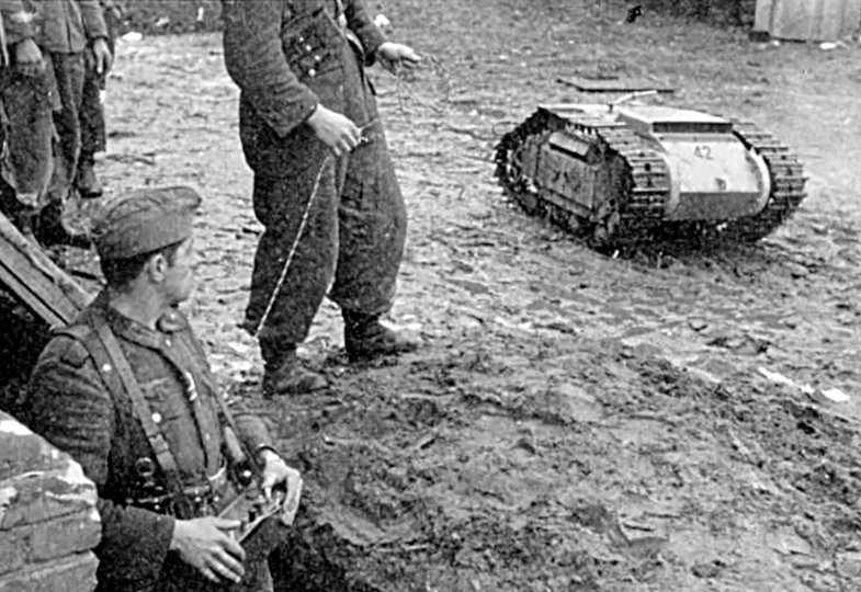Schwarz-Weiß Bild: Ein Soldat schaut nach unten auf einen kleinen Panzer