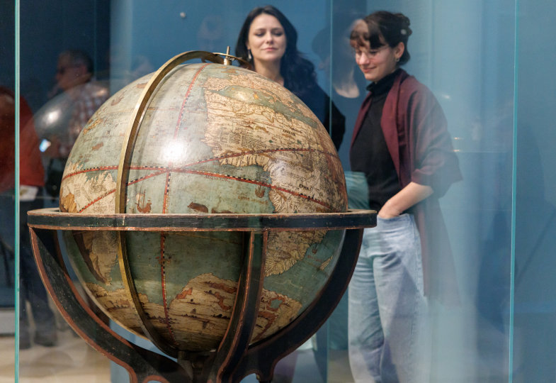 Zwei Frauen betrachten einen riesigen Globus.
