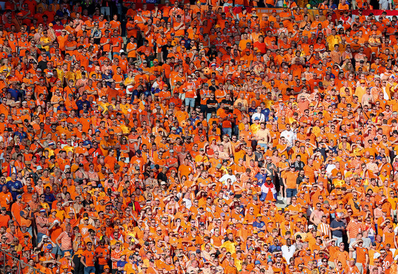 Jubelnde Menge im Fußballstadion, alle in Orange gekleidet.