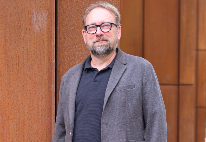 Porträt eines mittelalten Mannes mit Brille und blau-grauem Anzug