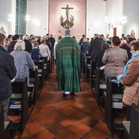 Priester und liturgische Dienste ziehen durch die versammelte Gemeinde zum Altar.
