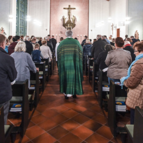 Priester und liturgische Dienste ziehen durch die versammelte Gemeinde zum Altar.
