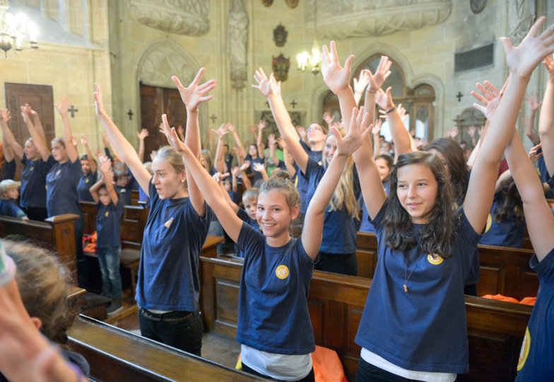 Kinder und Jugendliche heben beim Singen die Hände in die Höhe
