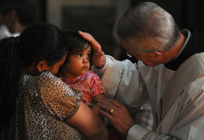 Ein Priester legt einem Kind die Hand auf