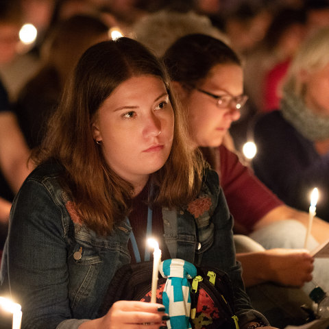 Jugendliche feiern mit Kerzen in den Händen Gottesdienst
