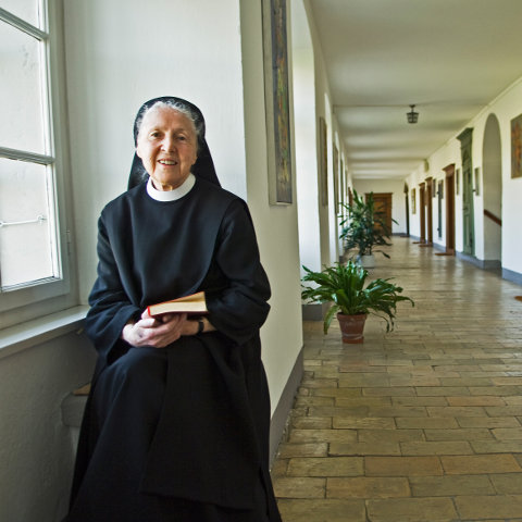 Die Benediktinerin Silja Walter mit Buch in der Hand an einem Fenster