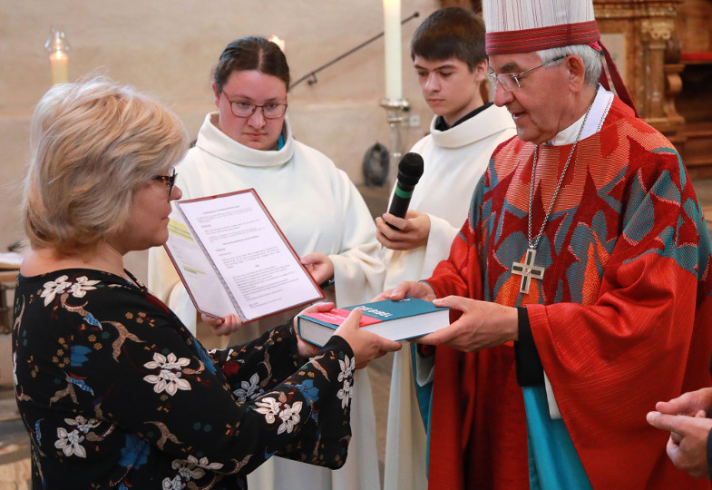Ein Weihbischof überreicht eine Bibel an eine neugesendete Gemeindereferentin