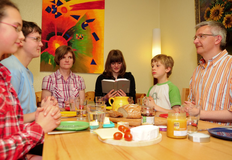 Eine Familie betet am Frühstückstisch