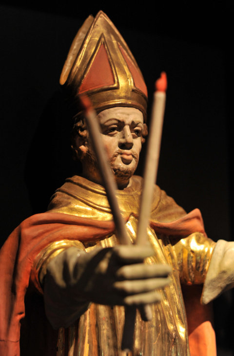 Eine Statue des heiligen Blasius hält zwei gekreuzte Kerzen in der Hand
