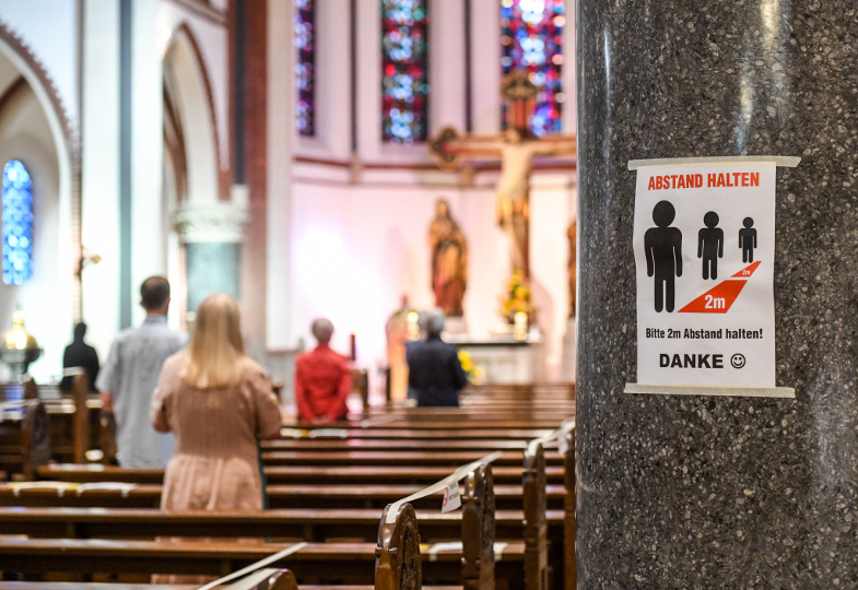 Ein Kirchenraum mit Absperrband an den Bänken und einem Hinweisschild zum Abstandhalten