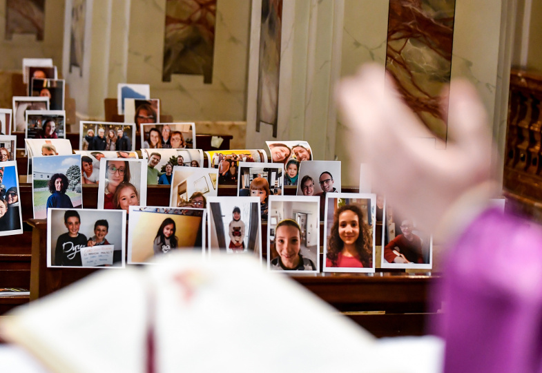 Während der Corona-Pandemie sind Selfies der Gläubigen in den leeren Kirchenbänken angebracht, während der Priester Eucharistie feiert