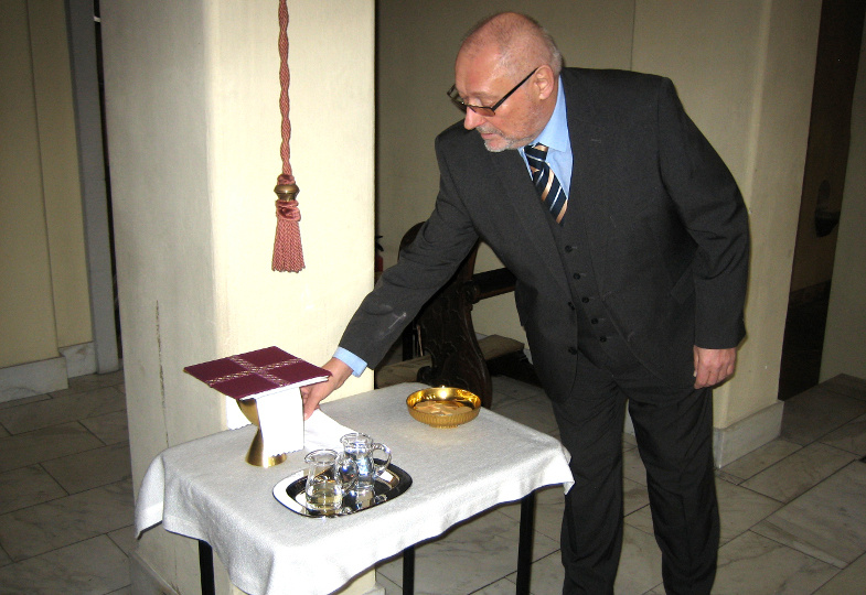 Ein Küster stellt auf der Kredenz die Gaben und Geräte für die Eucharistiefeier bereit