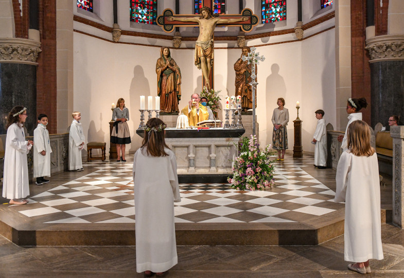 Erstkommunionkinder stehen in Abstand um den Altar.