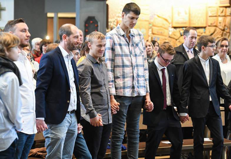 Jugendliche mit Behinderung und ihre Betreuer beten bei einem Firmgottesdienst
