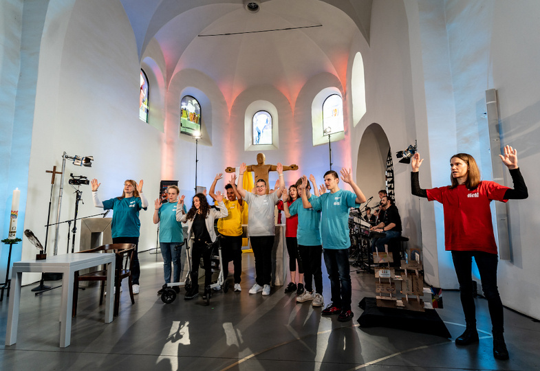 Menschen mit und ohne Behinderung beteiligen sich mit Gesten am Gottesdienst