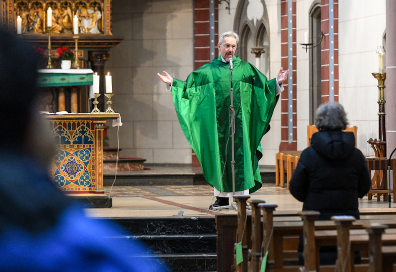 Priester breitet Hände aus zum litugischen Gruß