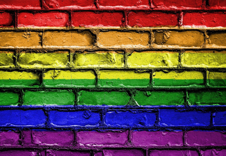 Eine gemauerte Wand ist in Regenbogenfarben angemalt.