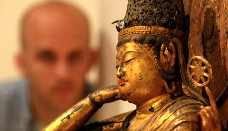 Mann betrachtet Buddha-Figur