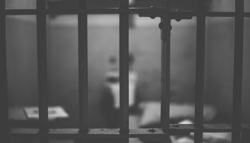 Blick durch Gitterstäbe in eine Gefängniszelle