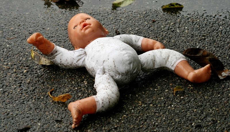 Puppe liegt im Straßendreck