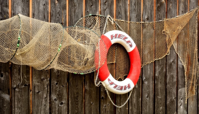 Fischernetz und Rettungsring vor Holzwand