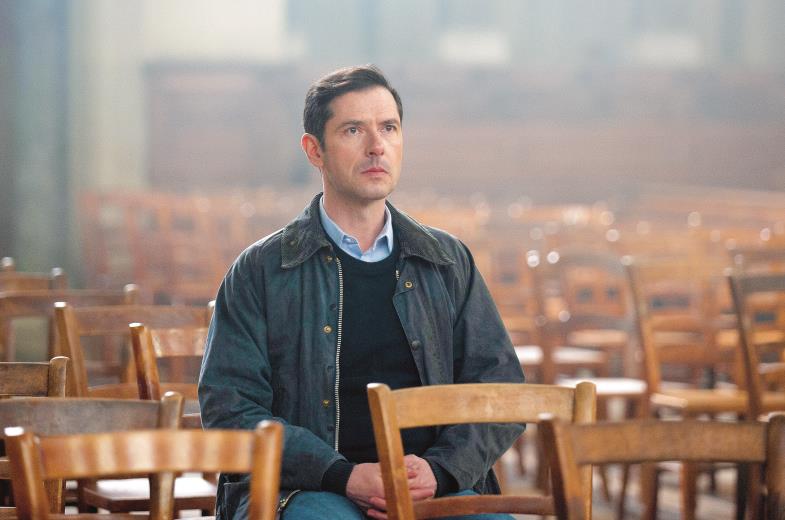 Junger Mann sitzt in leeren Stuhlreihen