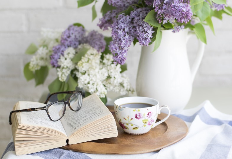 Ein Buch, eine Tasse Kaffee und Blumen auf einem Tisch