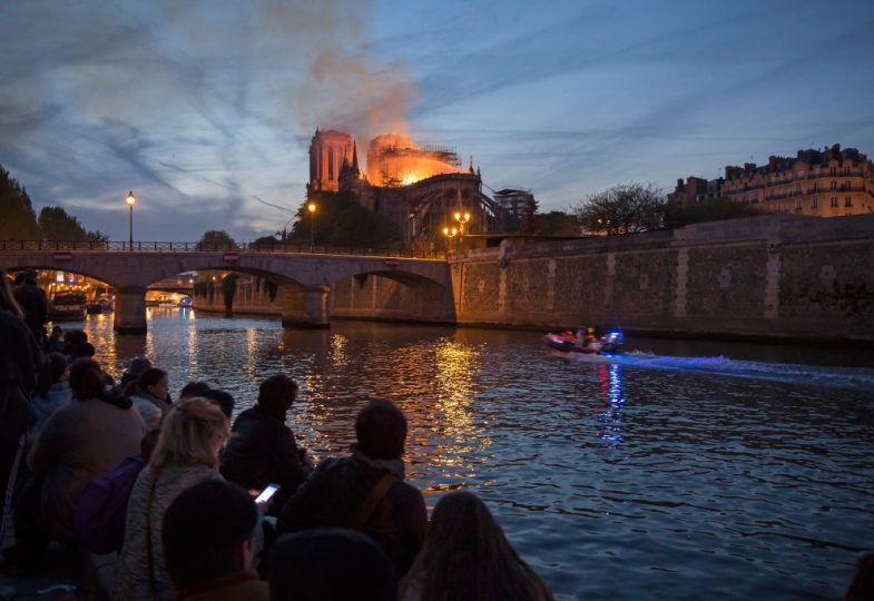 Menschen beobachten von einer Brücke den Brand der Pariser Kathedrale Notre Dame.