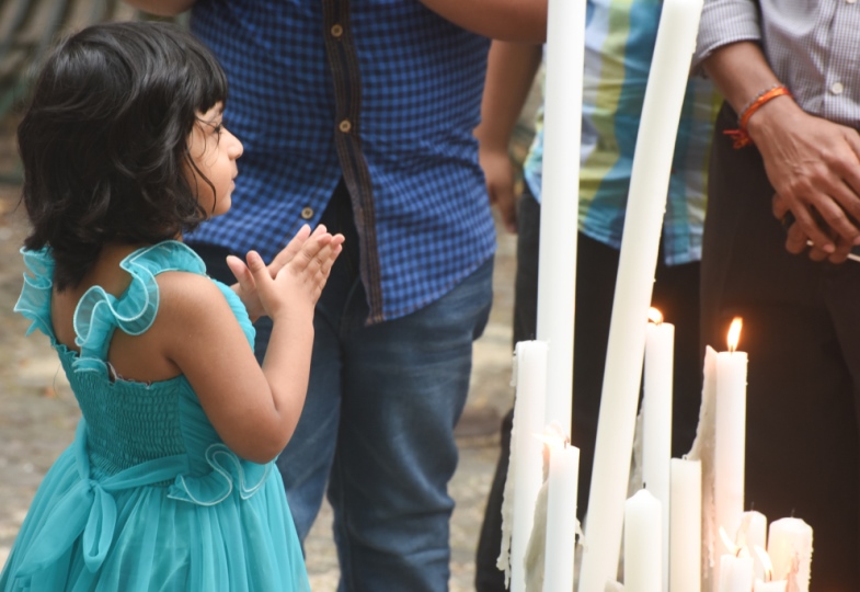 Ein kleines Mädchen aus Sri Lanka betet vor einigen Kerzen.