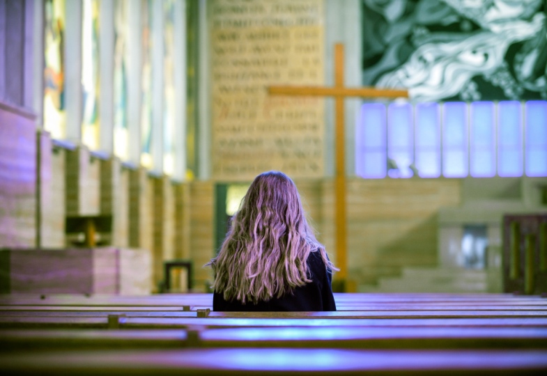 Eine Frau sitzt in einer Kirchenbank.