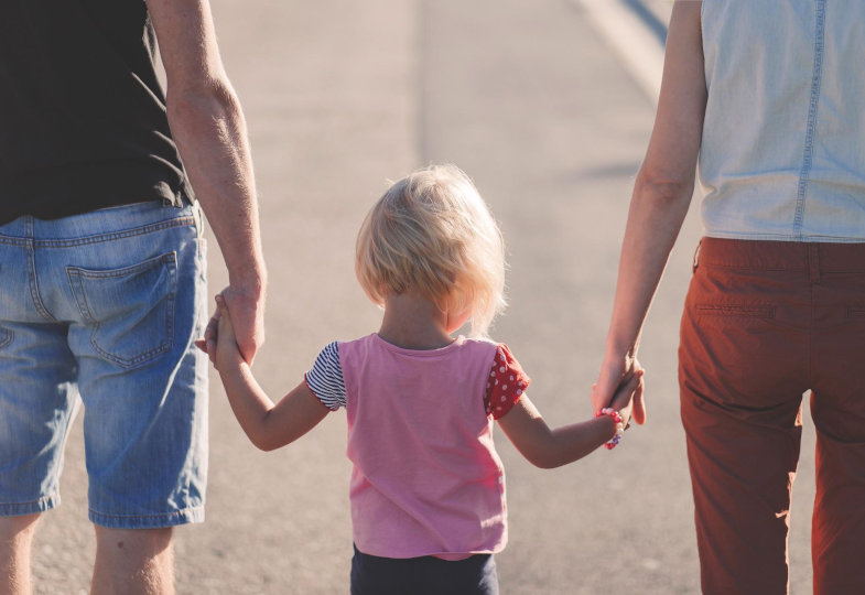 Mutter und Vater halten ihr Kind an der Hand