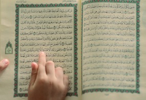 Hand auf Zeilen des Korans