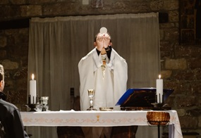 Ein Priester hebt eine Hostie zur Wandlung hoch