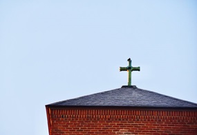 Auf einem Kirchdach thront ein Kreuz