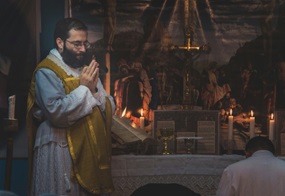 Ein Priester steht betend am Altar