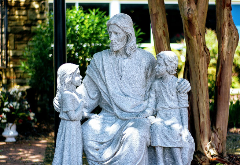 Eine Jesus-Statue, die ihn mit zwei Kindern zeigt