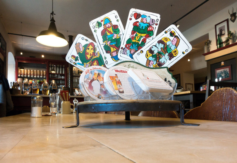 Auf einem Tisch stehen Bierdeckel und Spielkarten