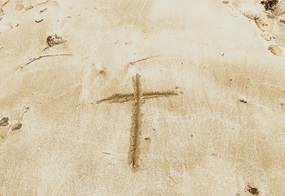Ein Kreuz ist in Sand gemalt